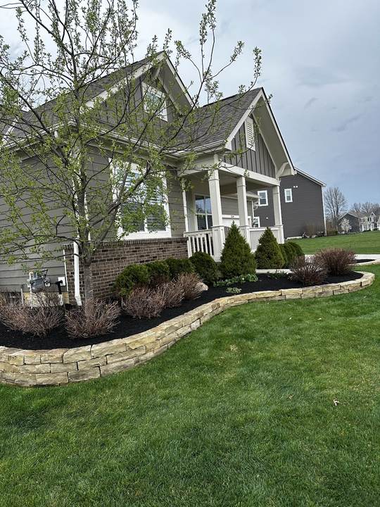 Planting bed with a stacked-stone border in front of a house