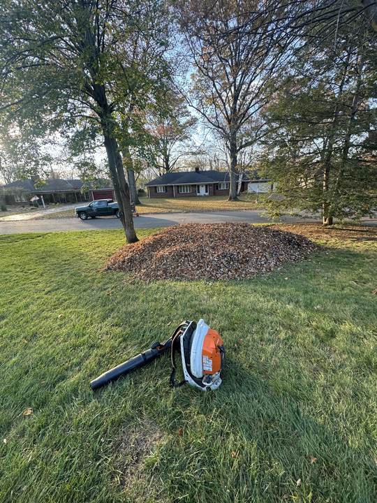 Leaf pile and a backpack blower on a lawn during a fall cleanup