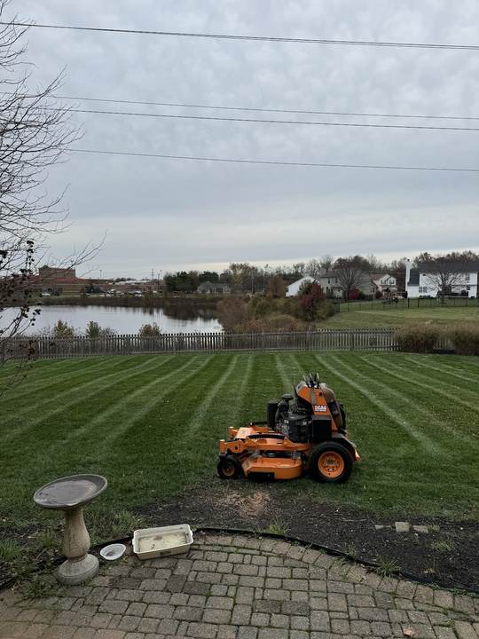 Striped backyard lawn between a brick patio and a pond