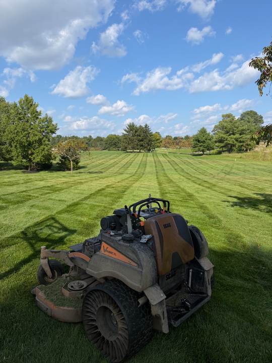 Stand-on mower parked on a freshly striped lawn