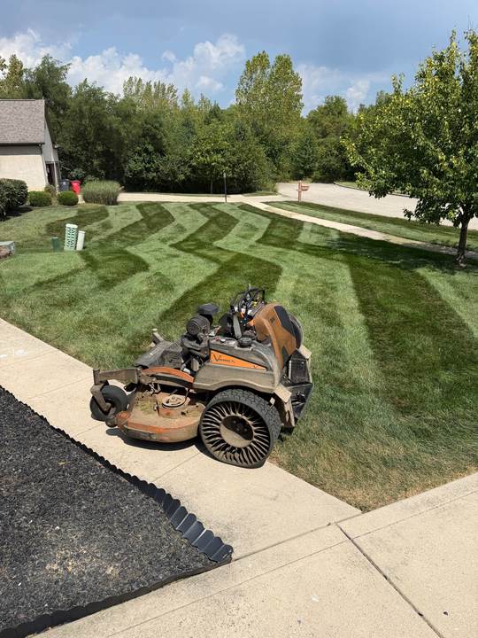Zigzag mowing stripes beside a driveway and a fresh mulch bed